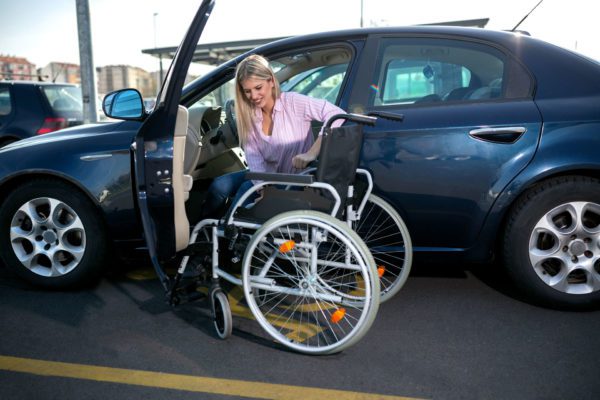 disabled girl getting into wheelchair from her dar